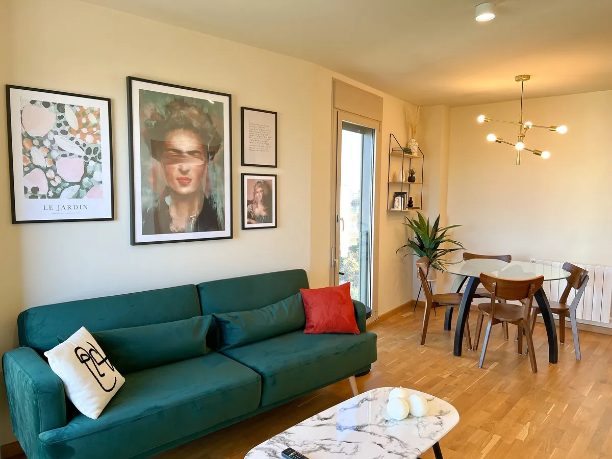 Zona living con divano verde e opere grafiche